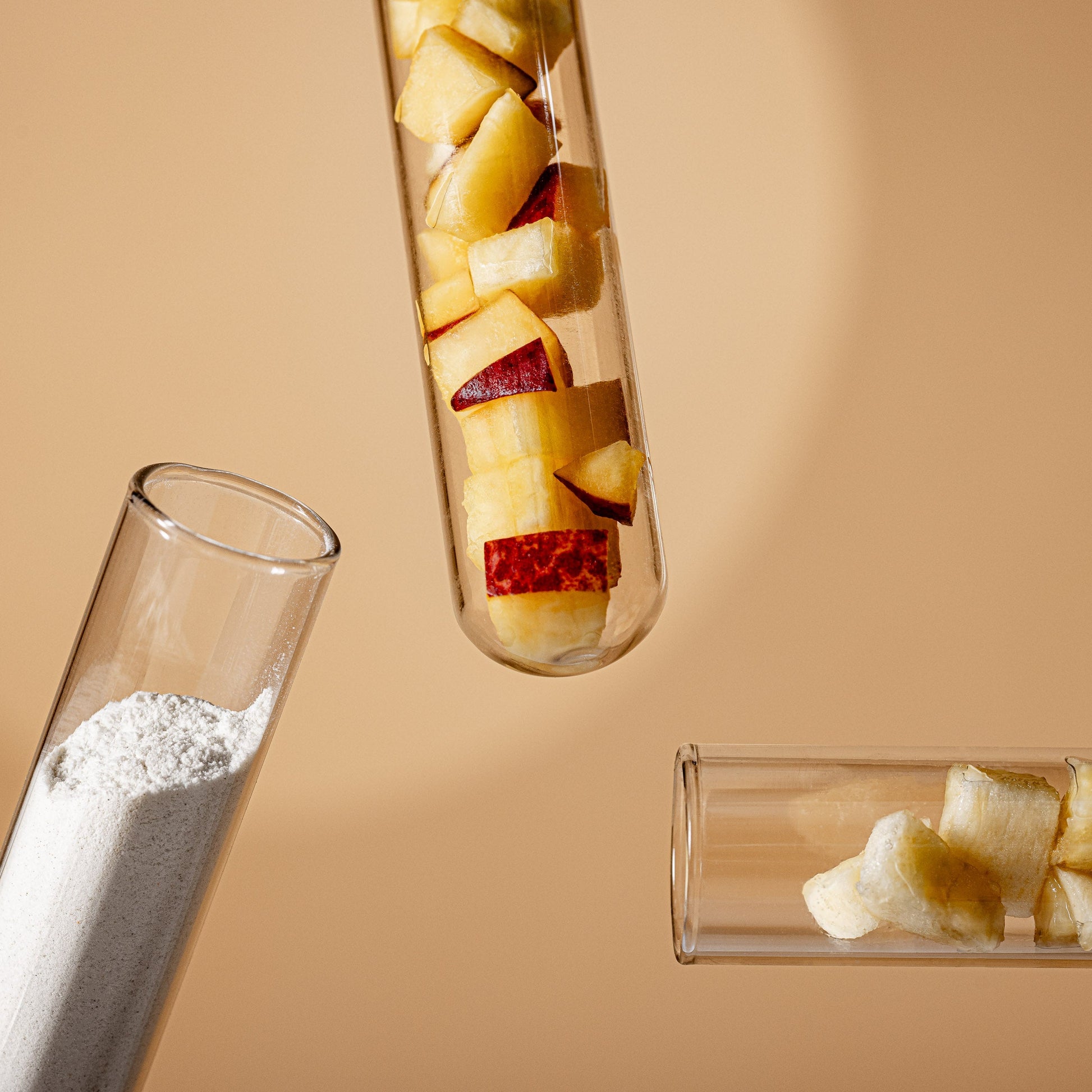 Three glass test tubes with fruit pieces on a beige background